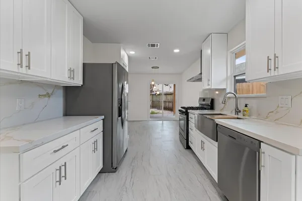 a kitchen with white cabinets and stainless steel appliances