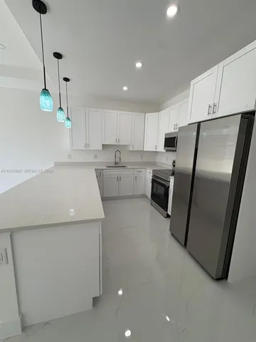 a kitchen filled with white cabinets and stainless steel appliances