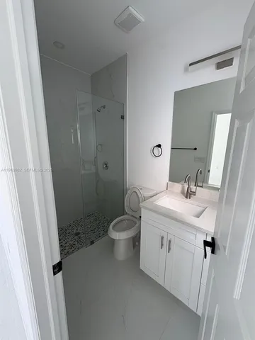 a bathroom with a granite countertop sink a toilet a mirror and vanity