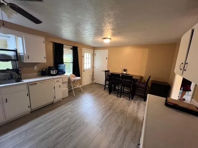 a kitchen with a sink dishwasher a dining table and chairs with wooden floor