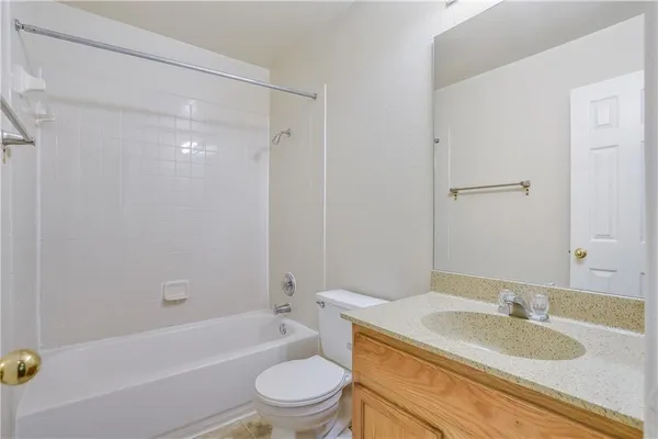 a bathroom with a granite countertop bathtub shower sink mirror vanity and toilet