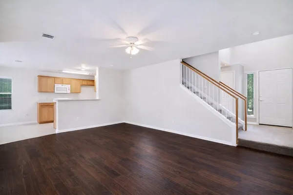 a view of an empty room with wooden floor and a ceiling fan