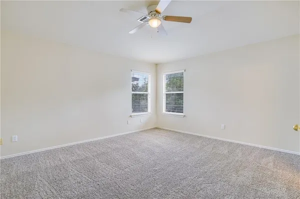 an empty room with windows and fan