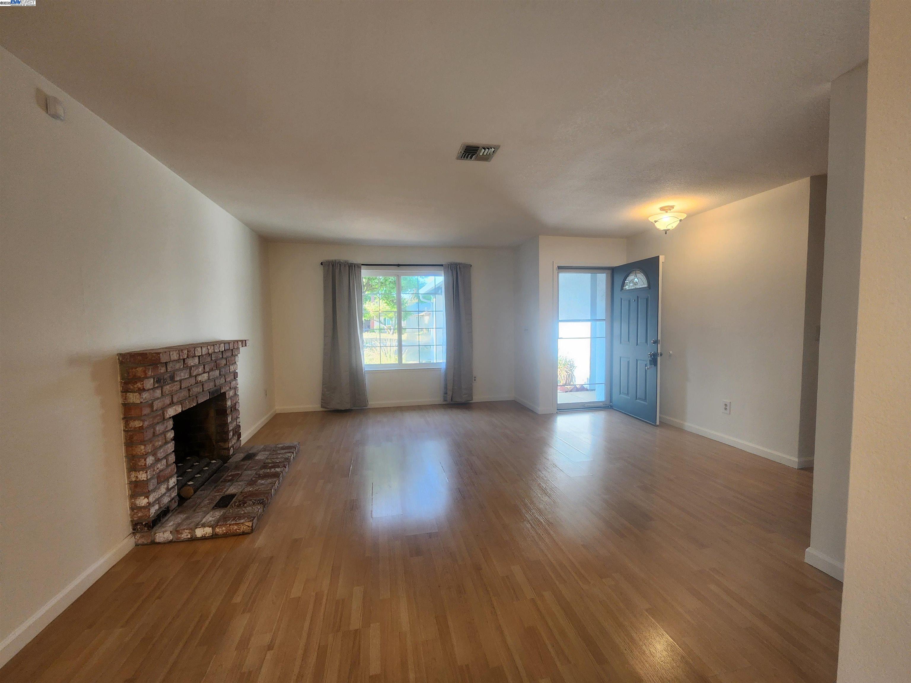 1733 Carnation Circle Livermore, CA 94551 - Photo 3 of 27 an empty room with windows a fireplace and wooden floor