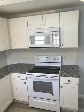 a kitchen with white cabinets and white appliances