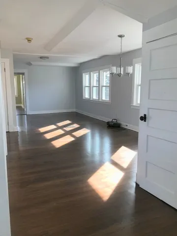 a view of empty room with wooden floor and window