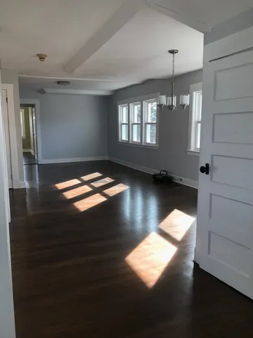 a view of empty room with wooden floor and window