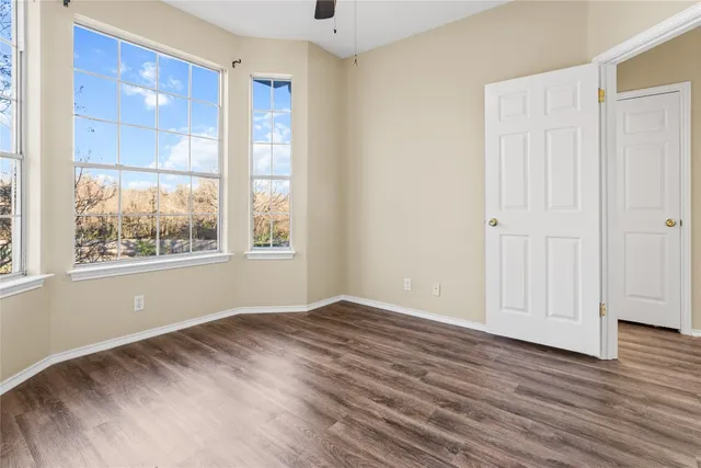 a view of an empty room with wooden floor and a window