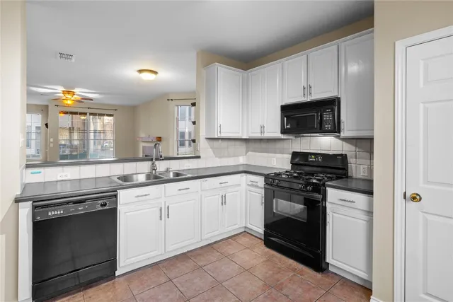a kitchen with stainless steel appliances granite countertop grey cabinets a stove a sink and a microwave