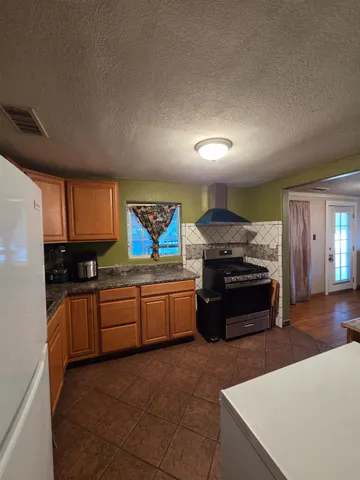 a kitchen with stainless steel appliances granite countertop a stove a sink and a refrigerator