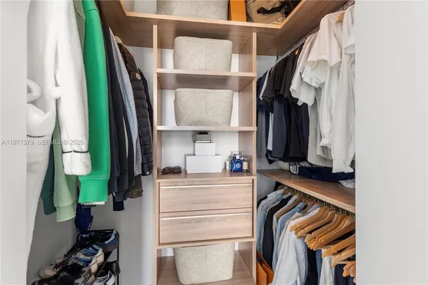 a view of walk in closet with clothes and shoes