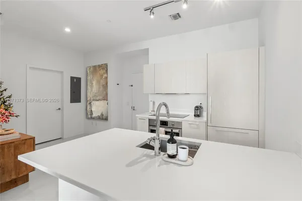a kitchen with a sink a stove and white cabinets