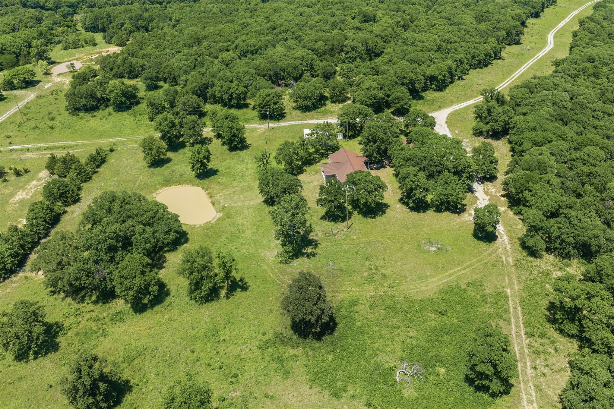 831 Barrons Ridge Wilson, OK 73463 - Photo 40 of 47 Expansive property featuring a single-story residence with a brown roof, surrounded by mature trees and lush green acreage