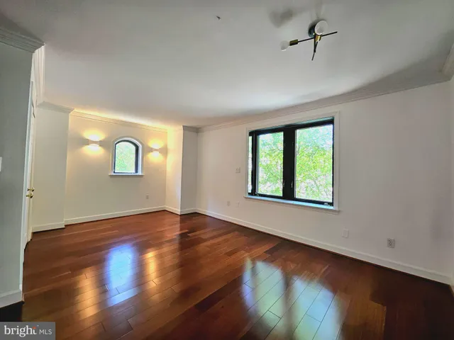 a view of empty room with wooden floor and fan