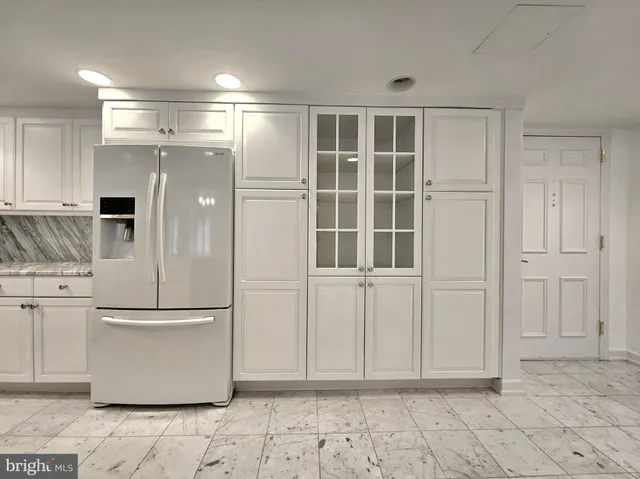 a view of a refrigerator in kitchen and an empty room