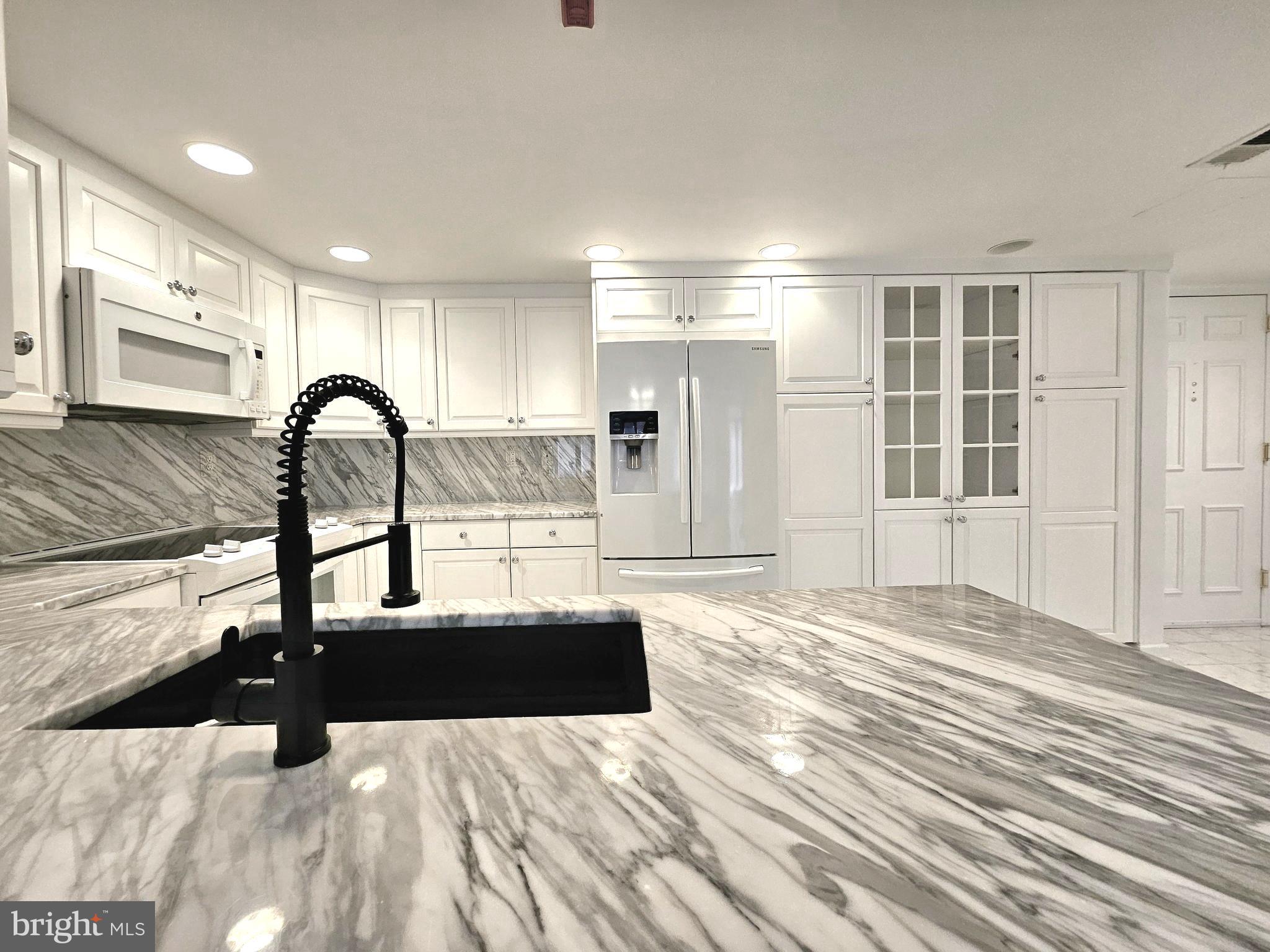1080 Wisconsin Avenue Northwest, Unit 103/104 Washington, DC 20007 - Photo 4 of 37 a kitchen with kitchen island a counter top space a sink and appliances