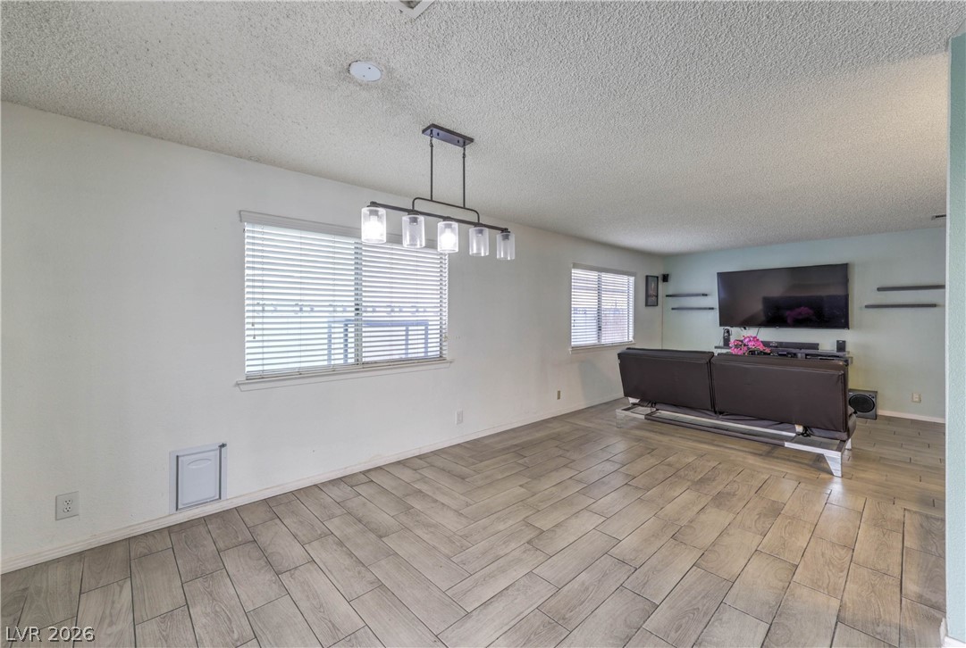 581 Carleton Drive Henderson, NV 89014 - Photo 9 of 37 Herringbone pattern tile flooring extends across a spacious living area, illuminated by natural light.