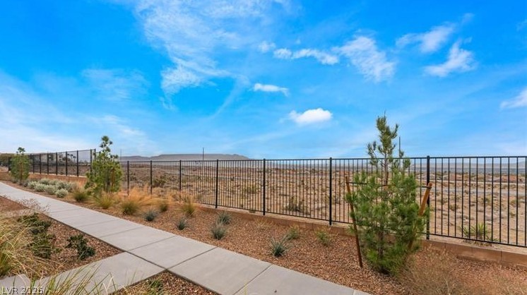 6212 Rathbone Street Las Vegas, NV 89166 - Photo 20 of 22 A well-maintained pathway leads to a vast open landscape, enclosed by secure fencing.