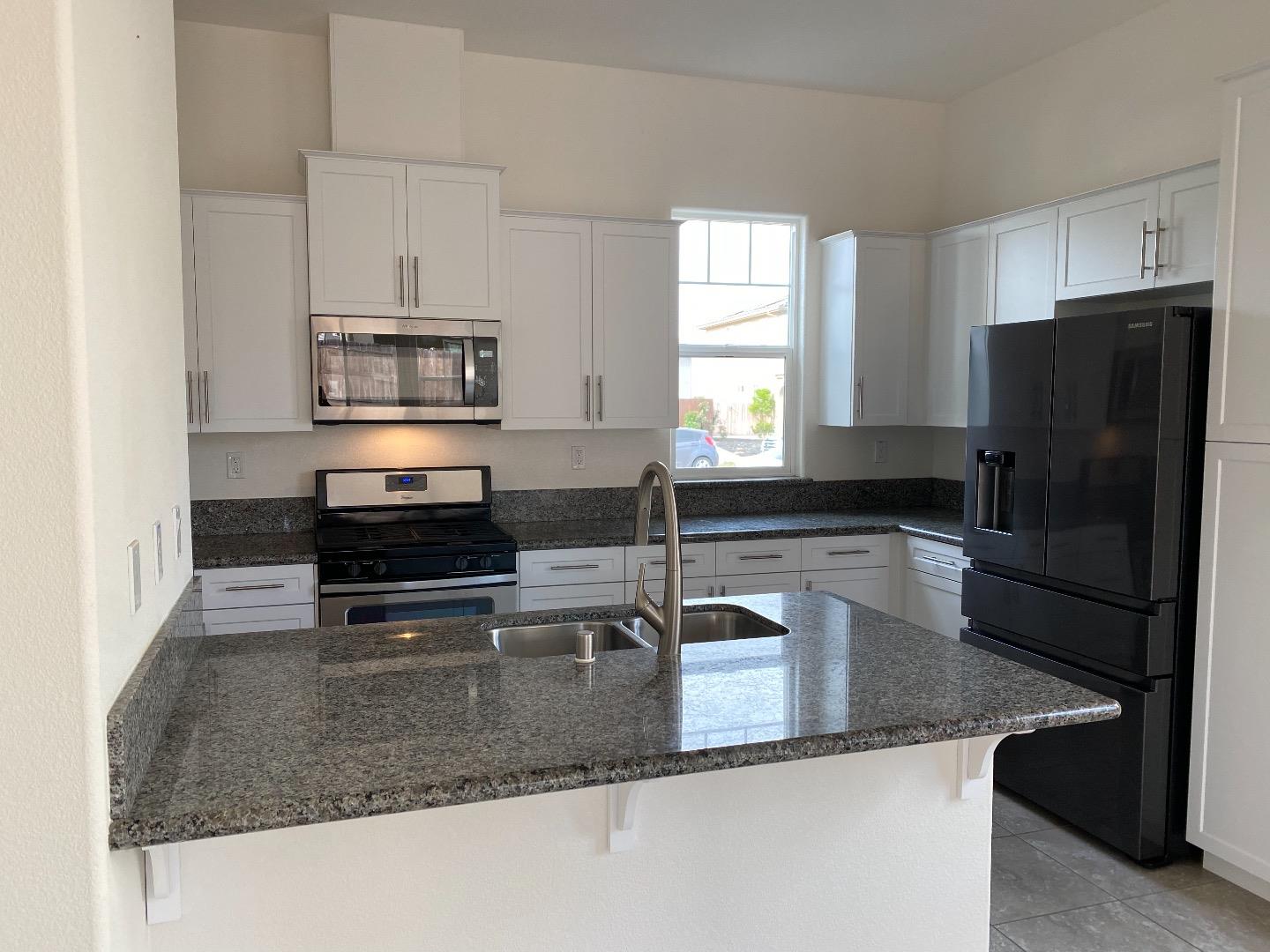 1233 La Colina Street Soledad, CA 93960 - Photo 4 of 10 a kitchen with granite countertop a refrigerator a stove a sink and a counter space