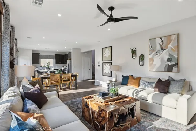 a view of a hallway to a livingroom with wooden floor and furniture