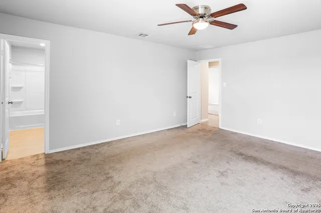 an empty room with ceiling fan and window
