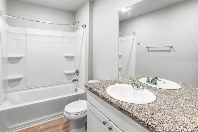 a bathroom with a granite countertop sink toilet a mirror and shower
