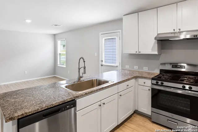 a kitchen with granite countertop a sink dishwasher stove and cabinets
