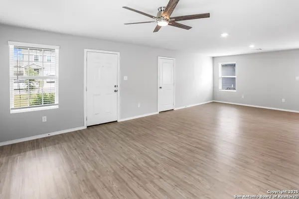 a view of an empty room with wooden floor and a window
