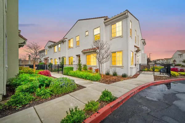 a front view of a multi story residential apartment building with yard and bench