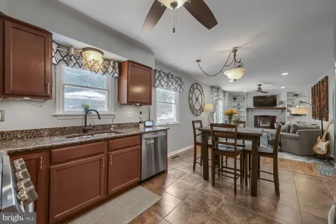 a kitchen with stainless steel appliances granite countertop a sink a stove a refrigerator cabinets and chairs