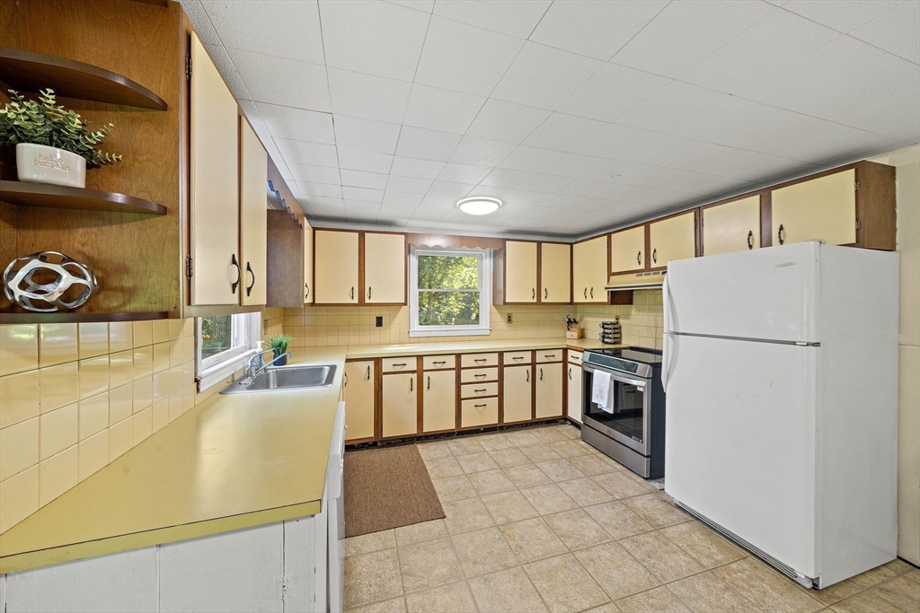 8 Elginwood Road Peabody, MA 01960 - Photo 4 of 25 a kitchen with a refrigerator a stove top oven and a counter top space
