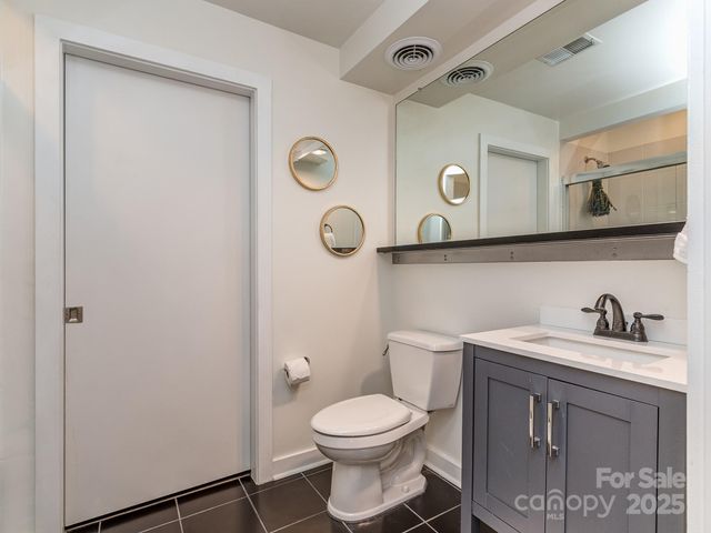 a bathroom with a toilet sink vanity granite and mirror