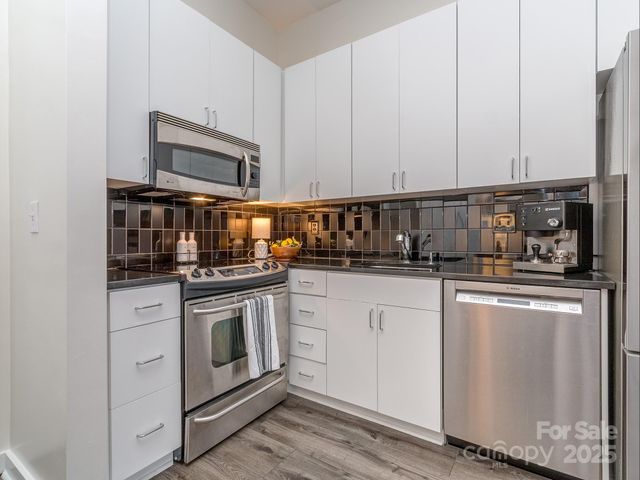 a kitchen with stainless steel appliances granite countertop white cabinets a sink and dishwasher