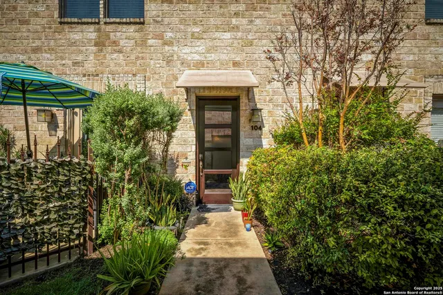 a pathway of a house with potted plants and a fountain