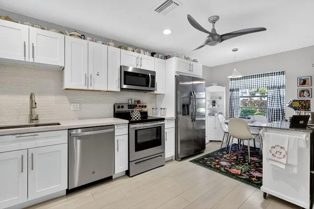 a kitchen with stainless steel appliances granite countertop a stove top oven a refrigerator a sink and dishwasher with wooden floor