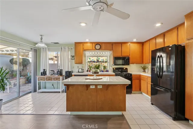 a view of a kitchen with kitchen island a stove a refrigerator a oven with a dining table and chairs