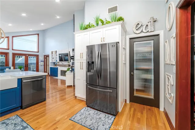 a kitchen with stainless steel appliances granite countertop a stove top oven a sink dishwasher and a refrigerator with wooden floor