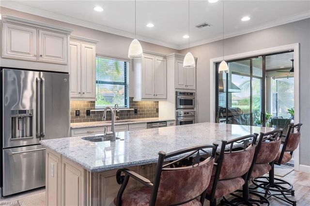 a kitchen with granite countertop a table chairs microwave and refrigerator