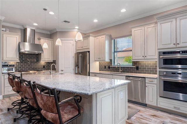 a kitchen with kitchen island granite countertop a table chairs sink stove and cabinets