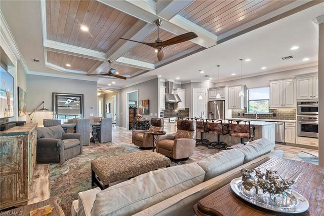 a living room with furniture kitchen view and a chandelier