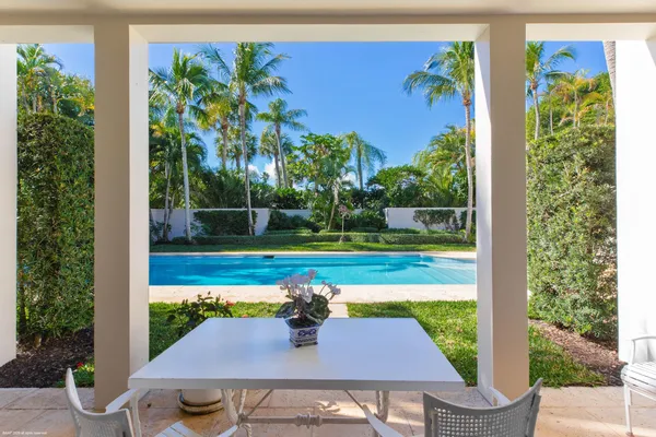 a view of a patio with table and chairs potted plants with wooden floor and palm tree