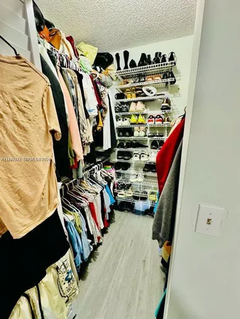 a view of walk in closet with clothes and shoes
