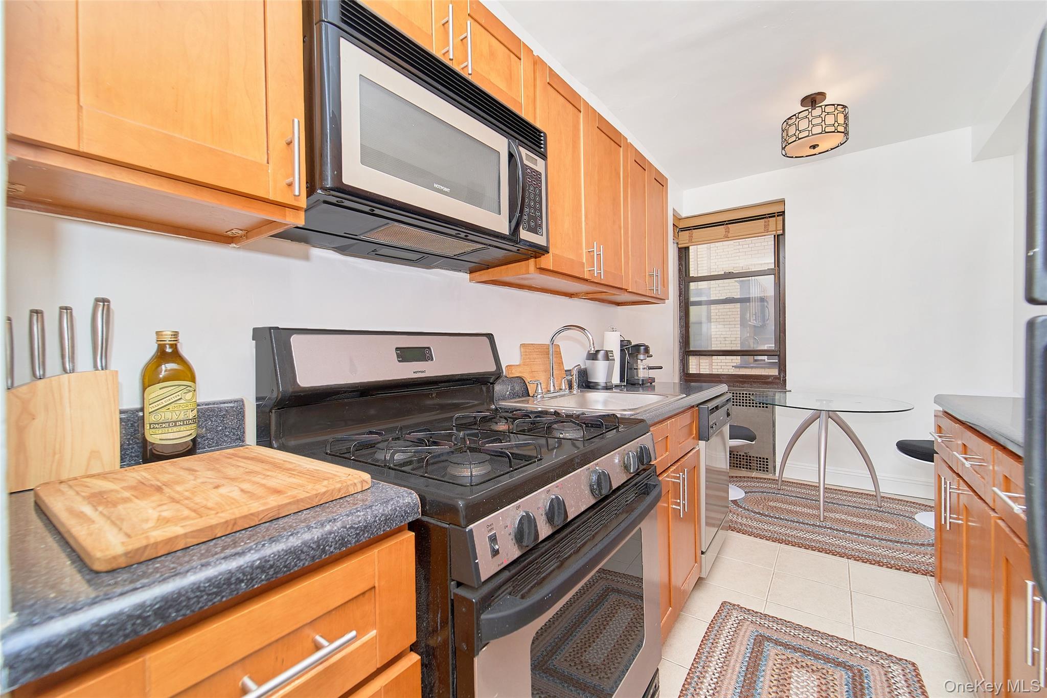 2962 Decatur Avenue, Unit 4D Bronx, NY 10458 - Photo 13 of 21 a kitchen with stainless steel appliances granite countertop a stove a sink and a microwave