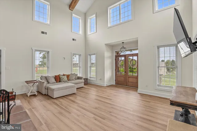 a picture of a livingroom with a dinning area hardwood floor a ceiling fan and windows