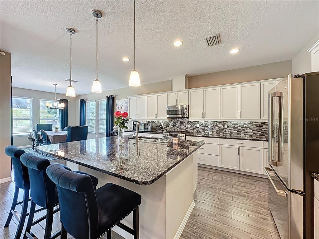 201 Silver Maple Road Groveland, FL 34736 - Photo 22 of 89 a kitchen with stainless steel appliances granite countertop table chairs a sink and a refrigerator