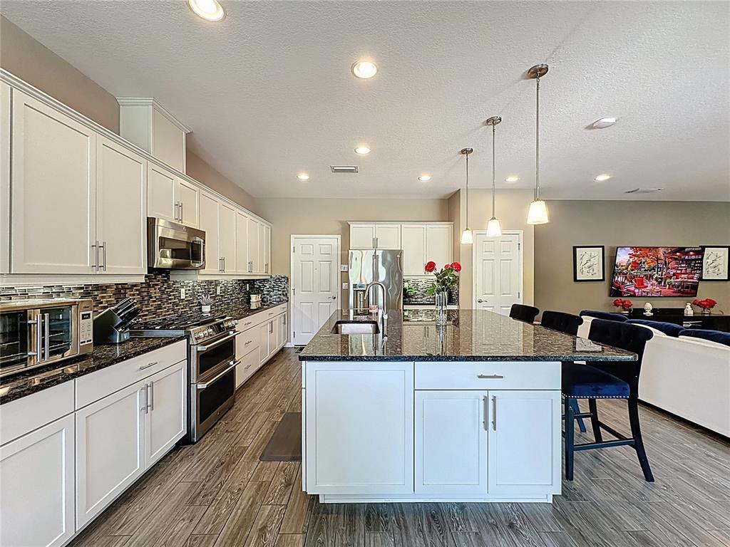 201 Silver Maple Road Groveland, FL 34736 - Photo 23 of 89 a large kitchen with stainless steel appliances a large center island attached withe living room