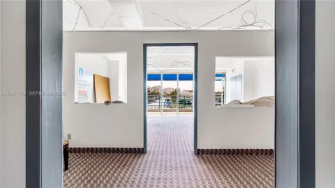 a view of a hallway with wooden floor and a bathroom