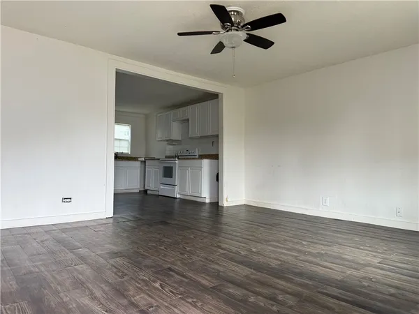 a view of empty room with wooden floor and window