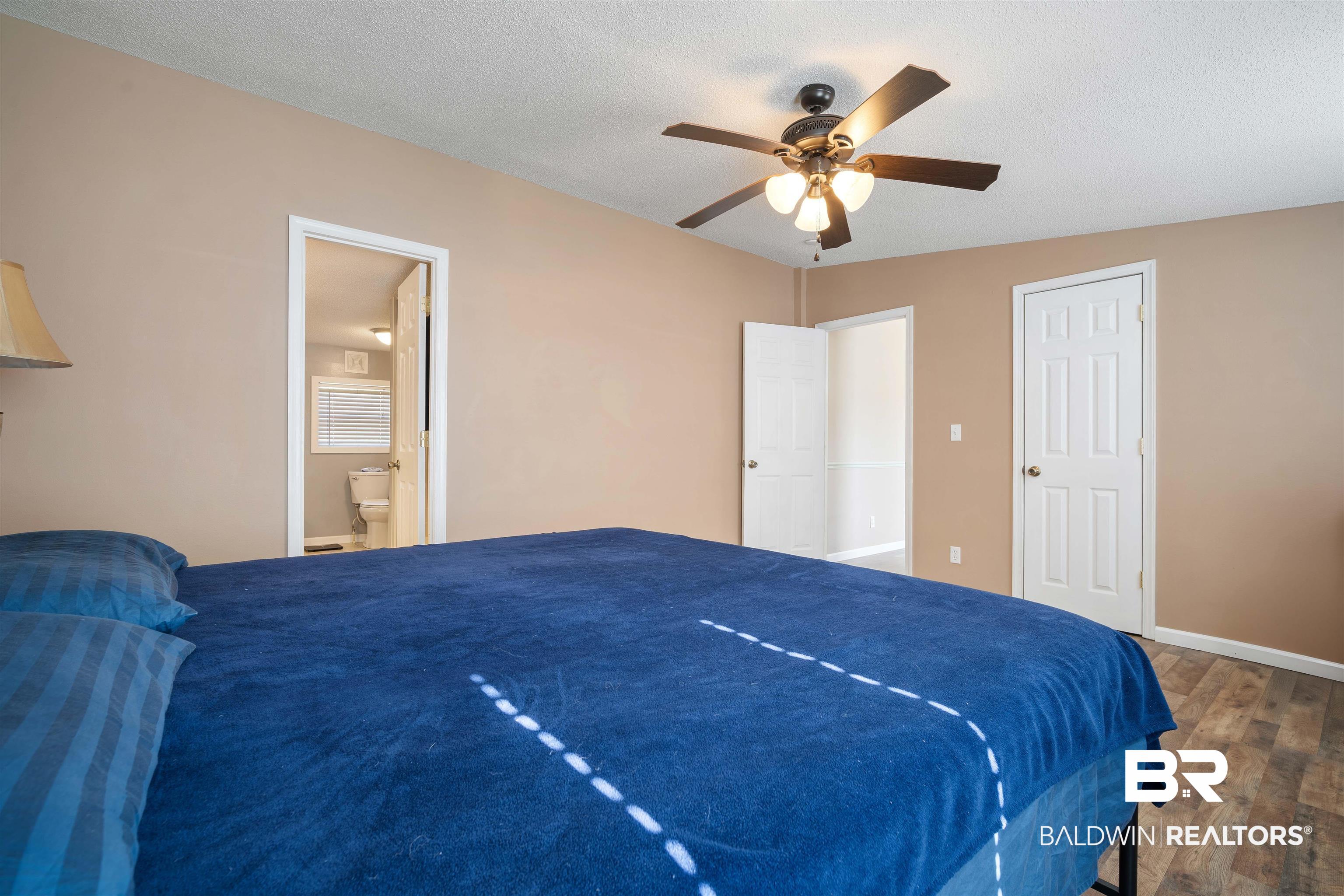 9011 Wilmer Georgetown Road Wilmer, AL 36587 - Photo 14 of 34 Bedroom featuring connected bathroom, baseboards, a textured ceiling, and wood finished floors