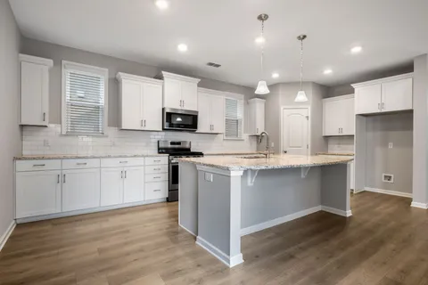 a kitchen with kitchen island granite countertop white cabinets and stainless steel appliances